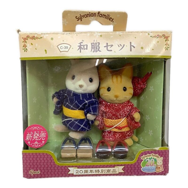 This enchanting Sylvanian Families 20th Anniversary Kimono Set features two adorable figures dressed in traditional Japanese attire. The figure on the left sports a dark blue kimono with a white diamond pattern and a vibrant yellow obi belt, while the figure on the right wears a striking red kimono adorned with delicate white and red floral designs, complemented by a gold obi. Complete with traditional zori sandals, this set beautifully captures the essence of Japanese cultural clothing. It serves as a charming representation of Japan's rich heritage and aesthetic.