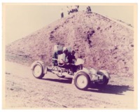 Two astronauts driving a test model of the lunar roving vehicle (LRV).