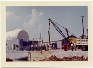 A Saturn rocket stage is loaded onto a barge on the Tennessee River.