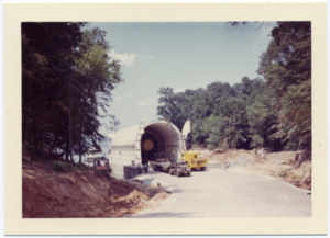 A Saturn rocket stage is loaded onto a barge on the Tennessee River.
