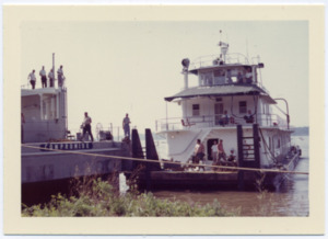 A Saturn rocket stage is loaded onto a barge on the Tennessee River.