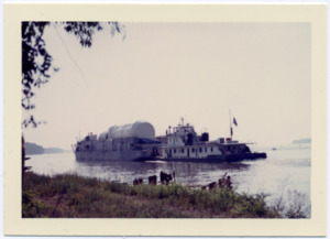 A Saturn rocket stage is loaded onto a barge on the Tennessee River.