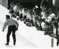 UAH men's hockey team members watch a game from the sidelines.