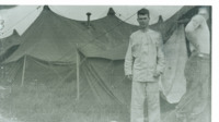 Photograph of a man outside of a tent at the 95th Evacuation Hospital.