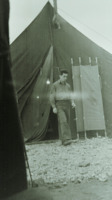 Photograph of a man smoking in front of a tent at the 95th Evacuation Hospital.