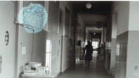 Photograph of a person on crutches walking down a hall in the 300th General Hospital in Naples, Italy.