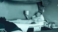 Photograph of a man reading in bed at the 300th General Hospital in Naples, Italy.
