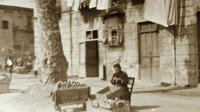 Photograph of a woman crafting something at a foodstand.