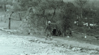 Photograph of a man outside a stick building in Italy.