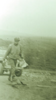 Photograph of a soldier with papers walking uphill from a military vehicle.