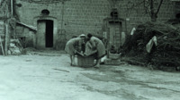 Photograph of multiple women doing laundry in a town in Italy.