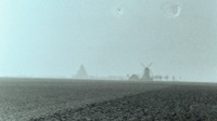 Photograph of French farmland with windmill in the background.