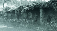 Photograph of two men in a garden.